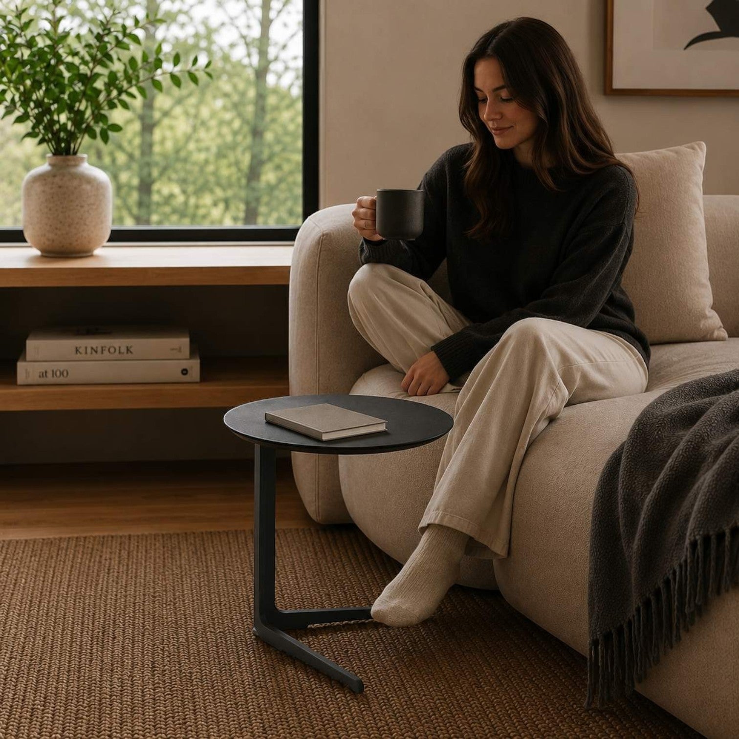 Addo Shop Flamingo low round side table with a black lacquered top and cantilever metal base in a cozy living room.