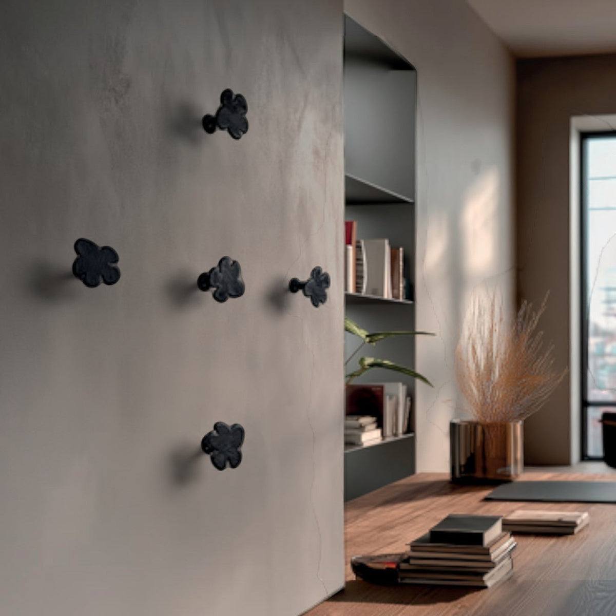 Addo Shop Beta Wall Hook, a set of five black, flower-shaped coat hooks mounted on a neutral wall.