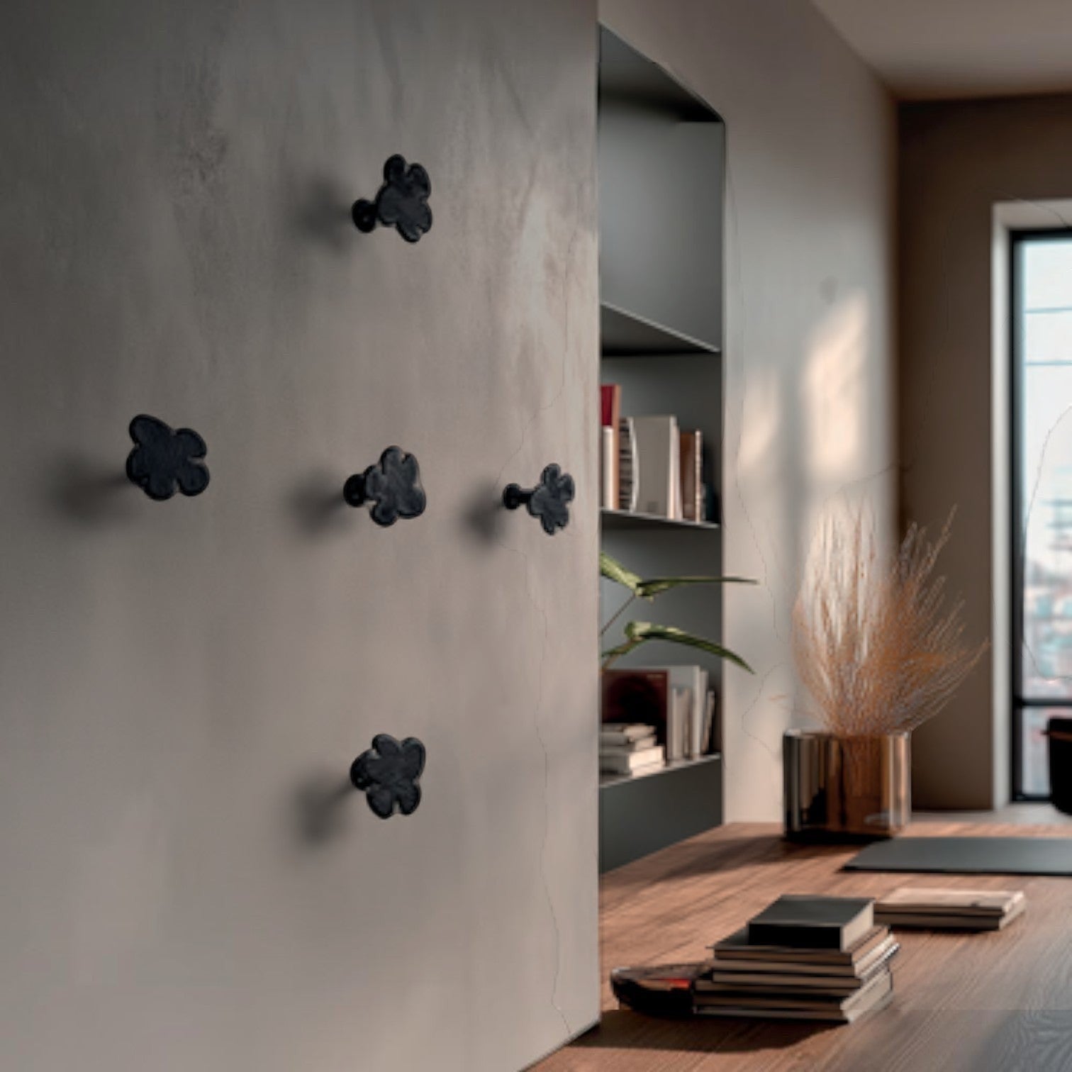 Addo Shop Beta Wall Hook, a set of five black, flower-shaped coat hooks mounted on a neutral wall.