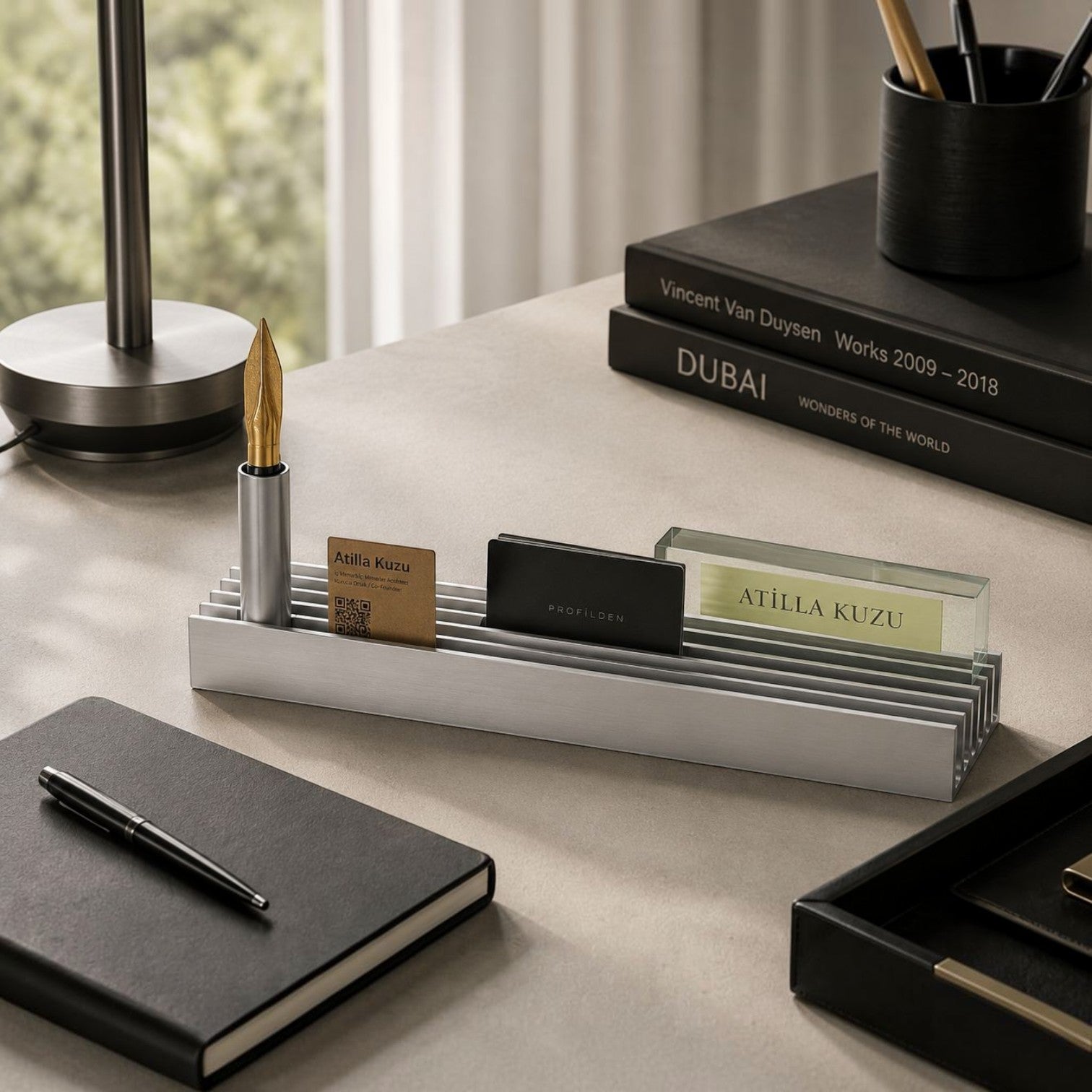 Addo Shop silver aluminum desktop business card and pen holder on a modern office desk with books and stationery