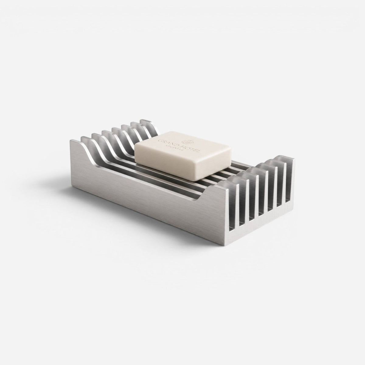 Addo Shop ARI brushed aluminum soap dish with a minimalist industrial design and a bar of soap on a white background.