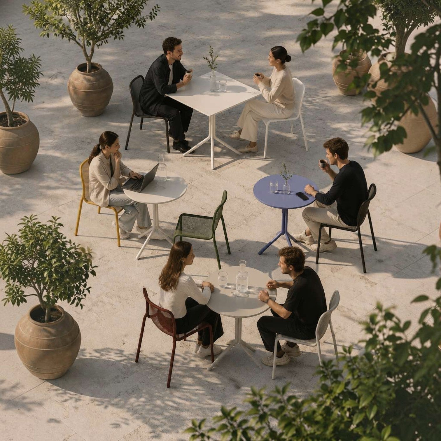 Addo Shop Bob dining tables in round and square shapes with powder-coated steel bases in a modern outdoor cafe setting.