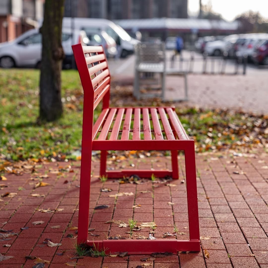 Addo Shop CORTINA.026 red metal outdoor bench with backrest, 120 cm long, placed on a paved walkway.