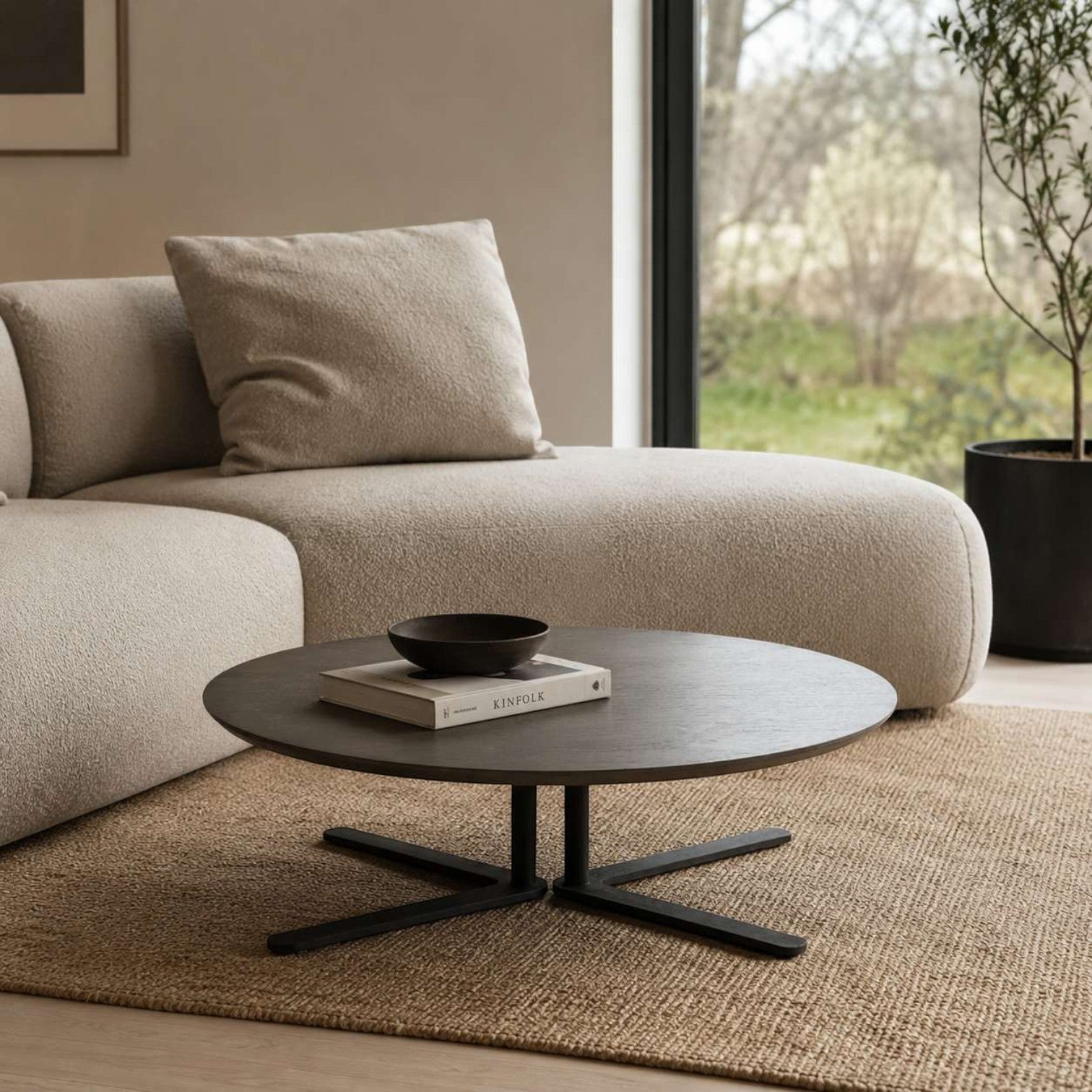 Addo Shop Dodo round low coffee table with a dark wood top and black metal cross base in a modern living room setting.