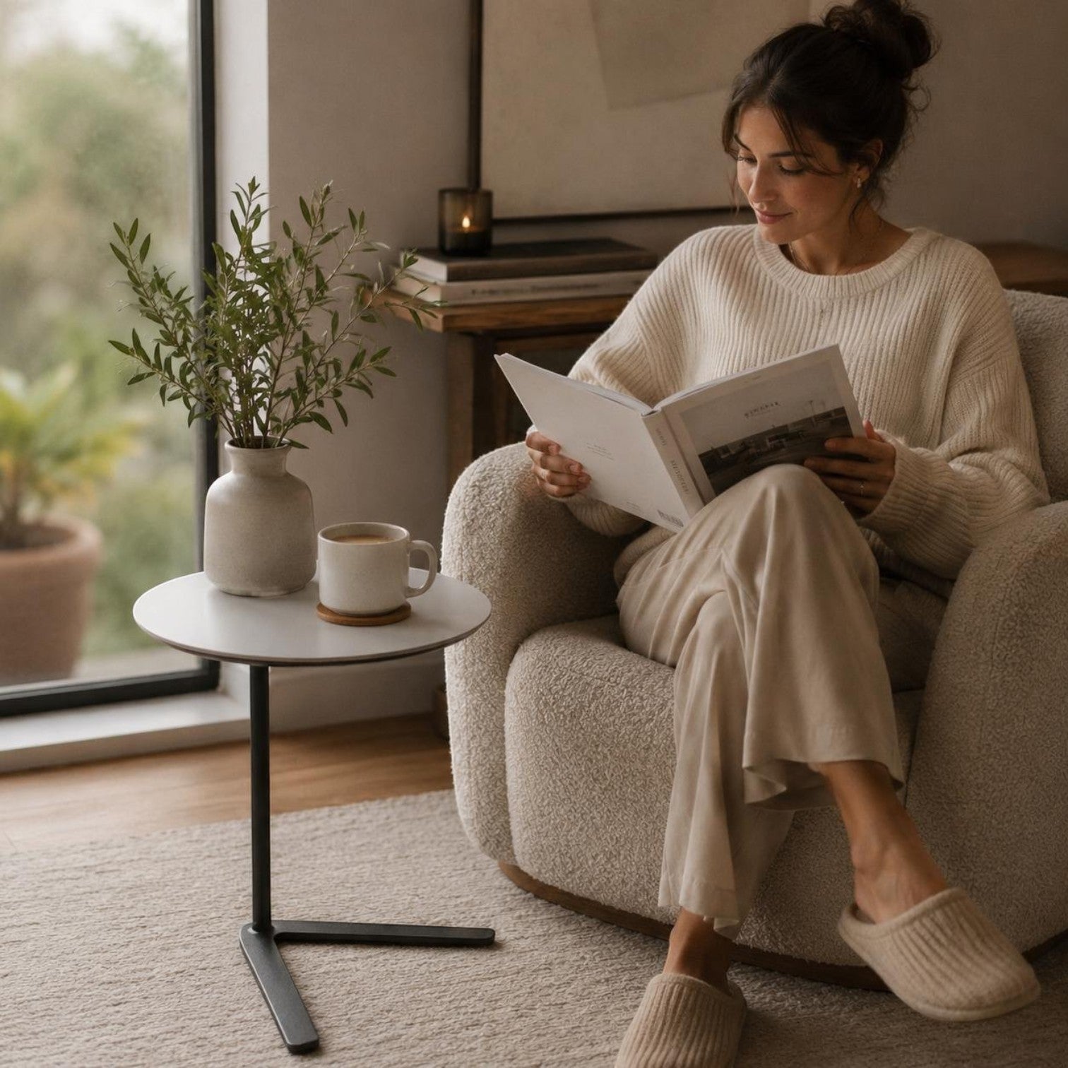Addo Shop Dodo side table with a round white top and black cantilever base next to a woman reading in a lounge chair.