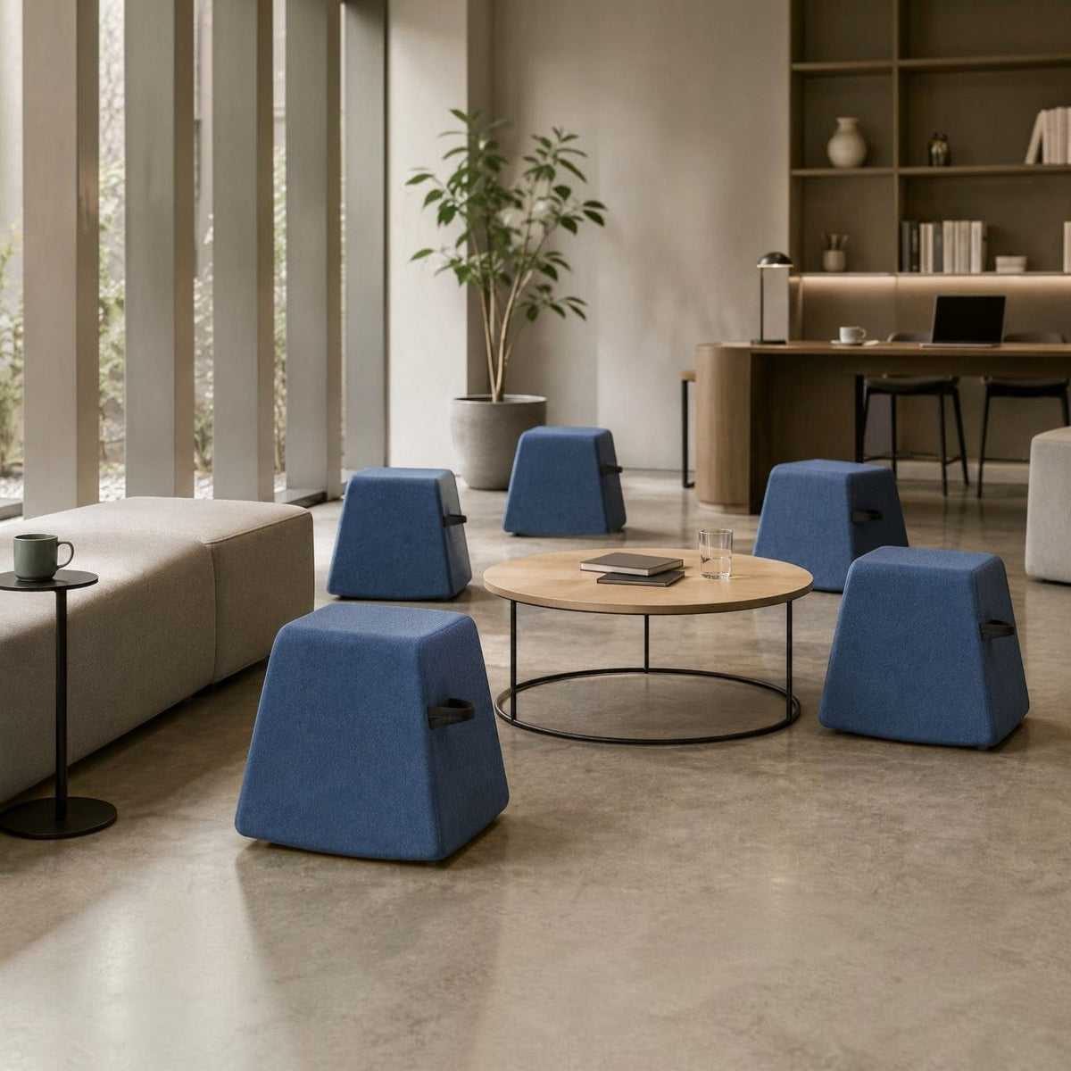 Addo Shop Dondolo blue fabric poufs with integrated handles arranged in a modern office lounge area.