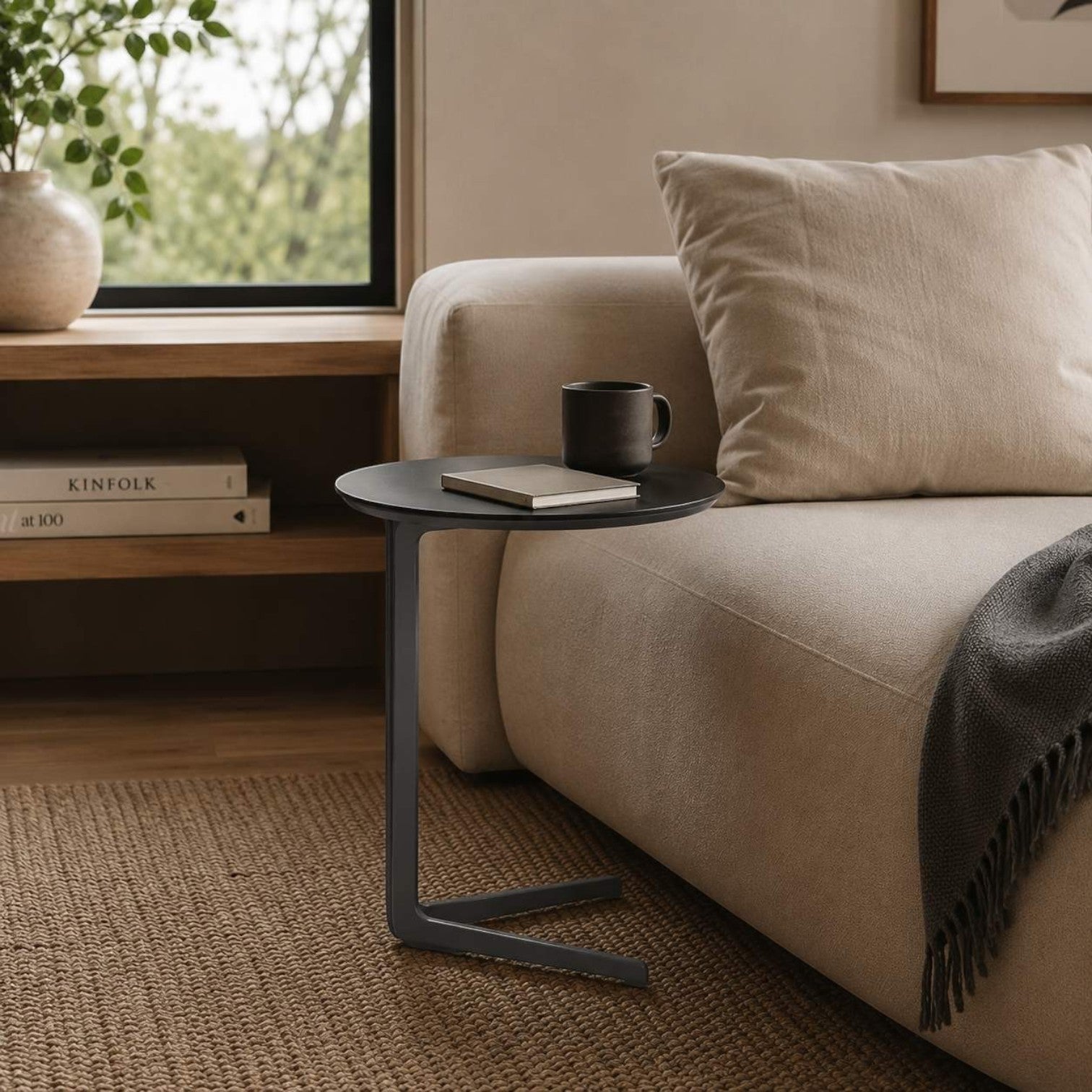 Addo Shop Flamingo High Round Table with a black metal frame beside a beige sofa in a modern living room