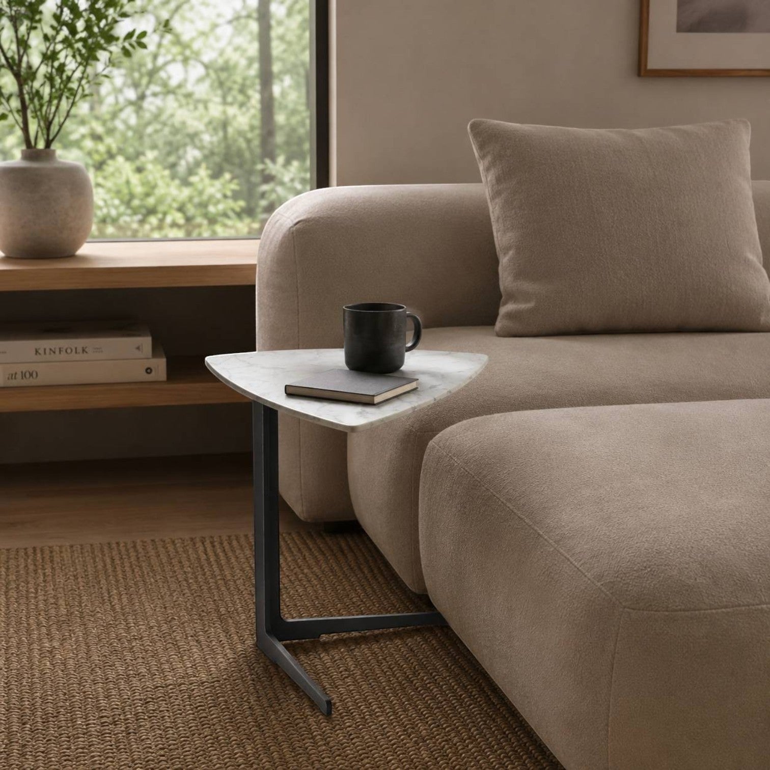 Addo Shop Flamingo High Triangle Side Table with a white marble top and black metal base next to a beige sofa