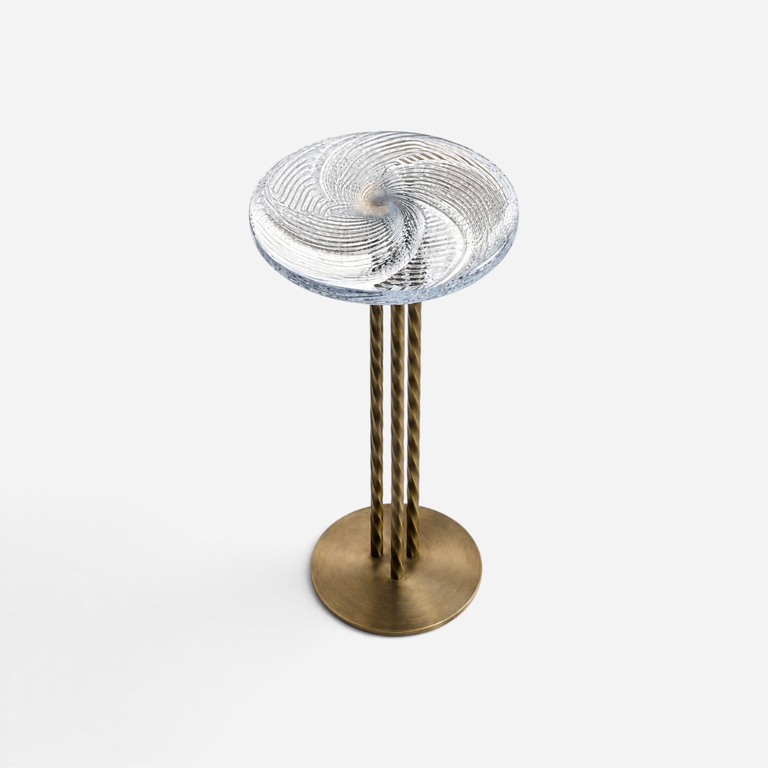 Addo Shop side table with a clear glass swirl top and three twisted antique brass metal legs on a round base.