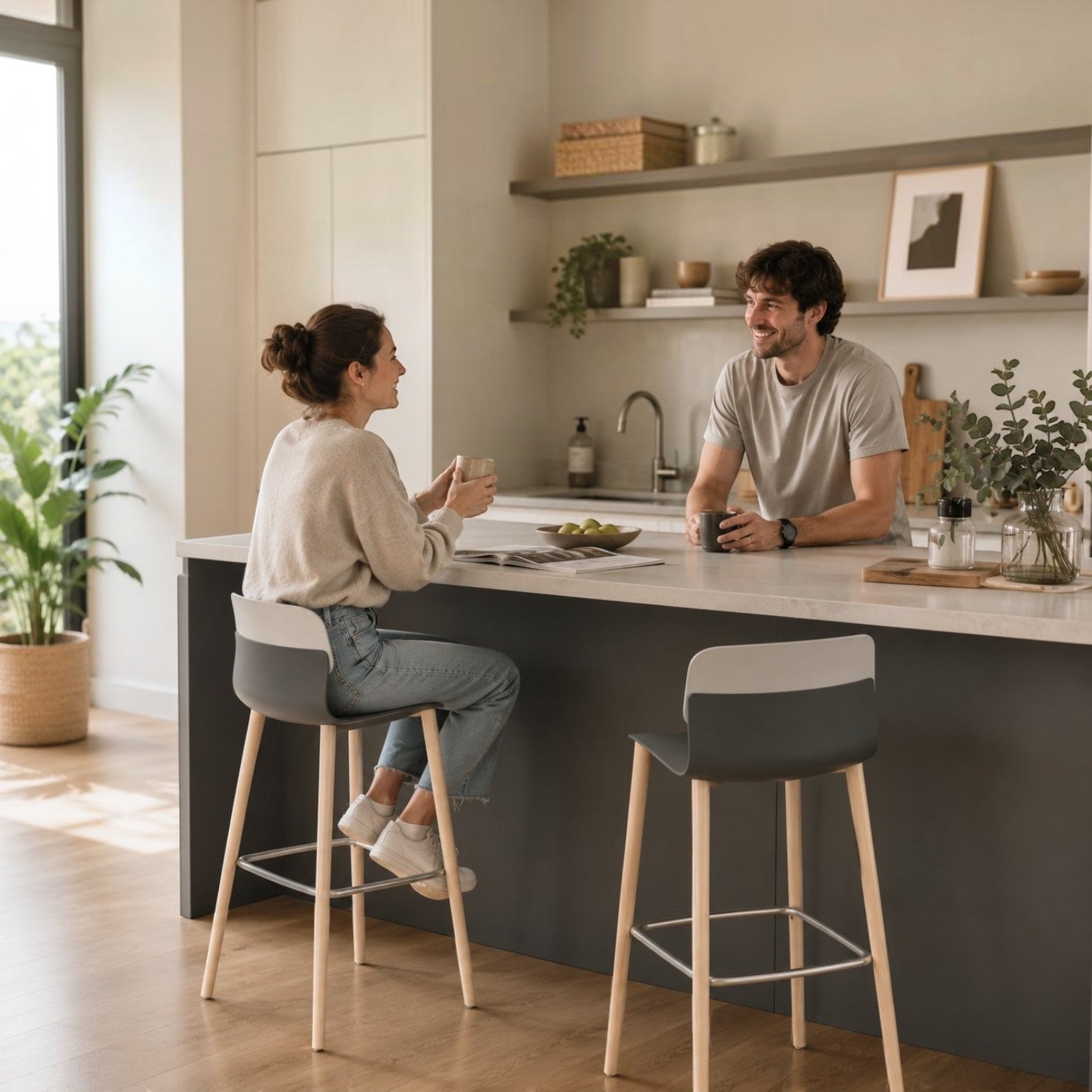 Addo Shop Greta bar stools with grey seats and light wood legs in a modern kitchen with a couple chatting