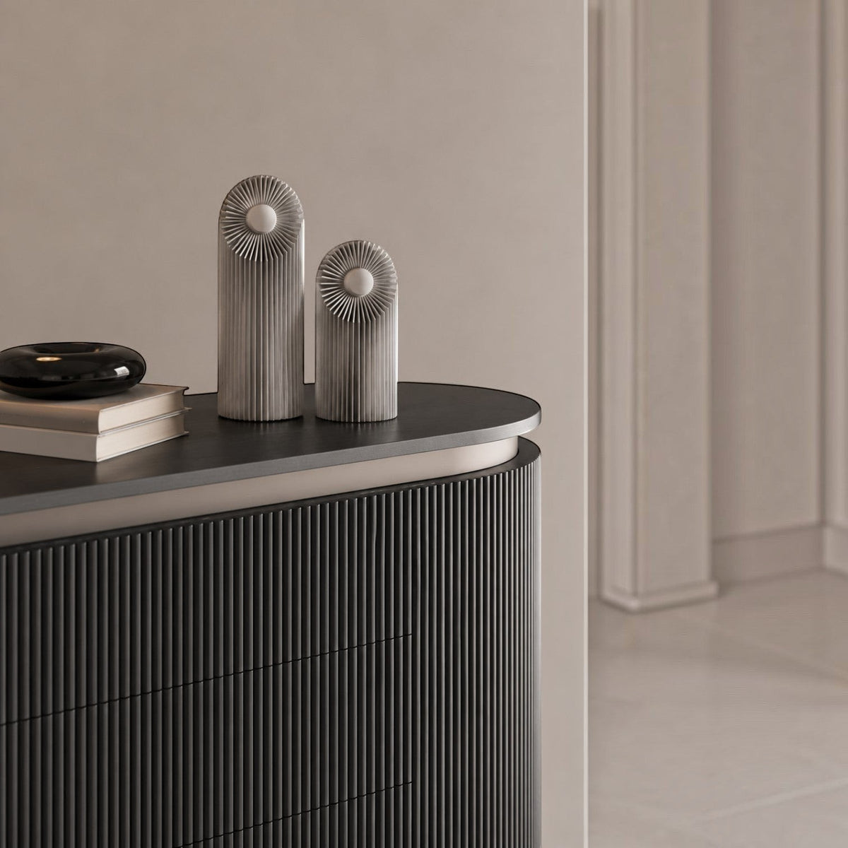 Addo Shop HELIO brushed aluminum sculptural decorative objects with a floral geometric design on a dark sideboard.