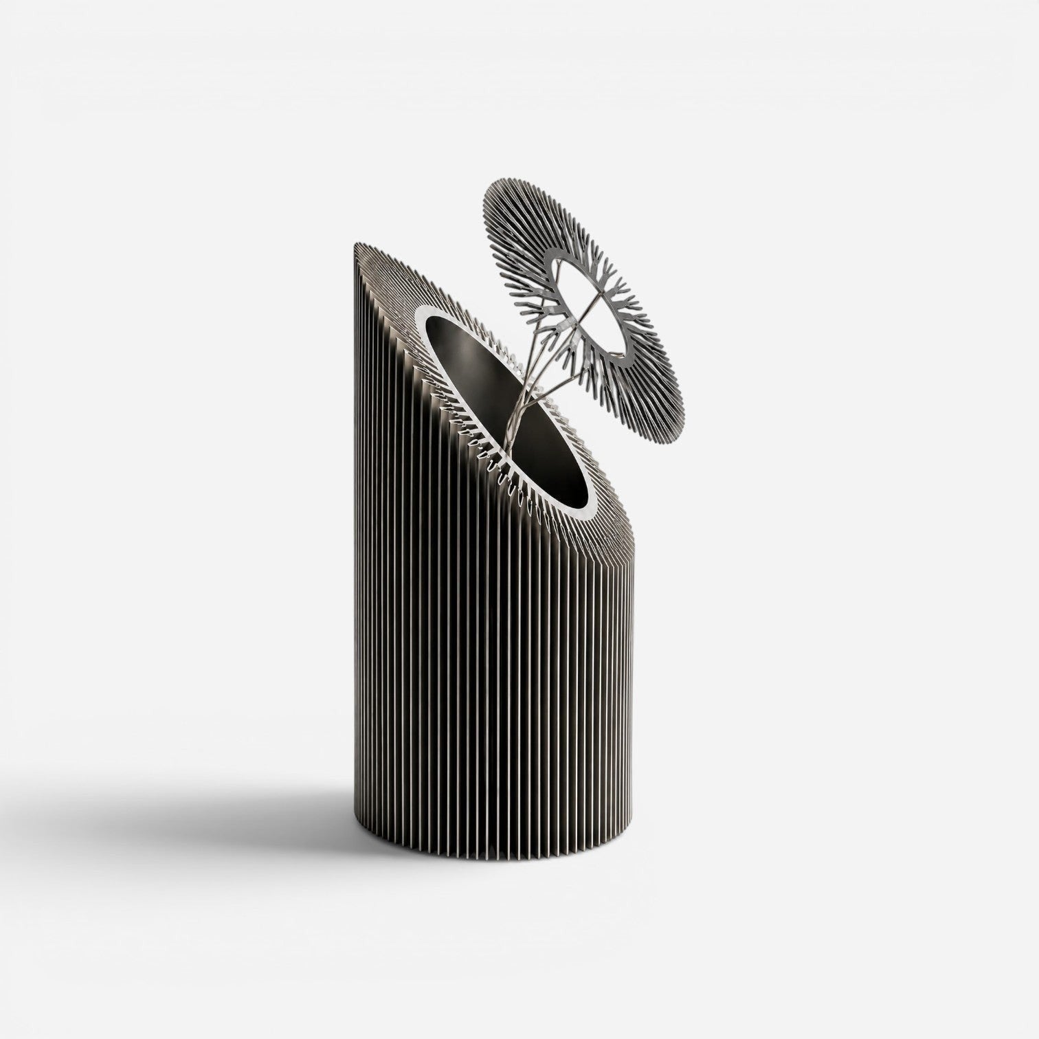 Addo Shop Helio I sculptural metal art piece with a cylindrical ribbed base and a delicate sun-like top element.
