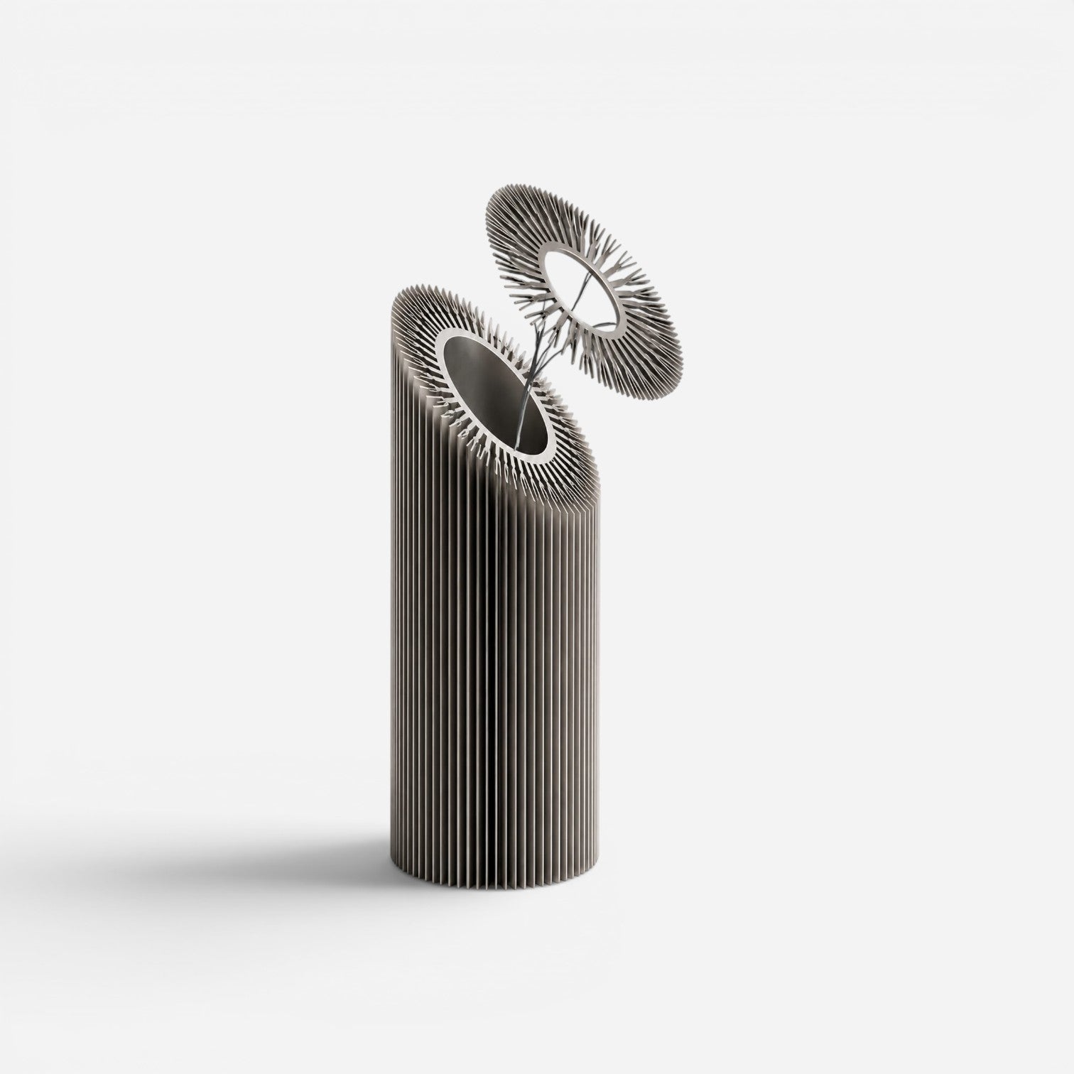 Addo Shop Helio I sculptural metal decorative object with a ribbed cylindrical body and a circular top detail.