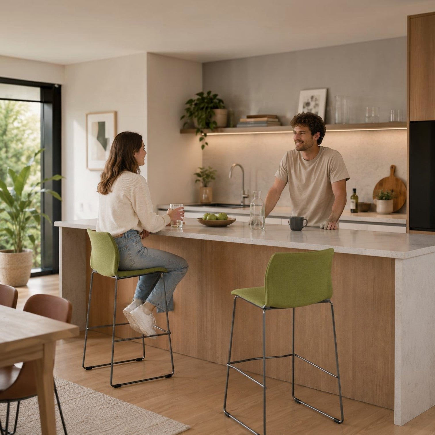 Addo Shop Incontro upholstered bar stools with green fabric seats and steel sled bases in a modern home kitchen.
