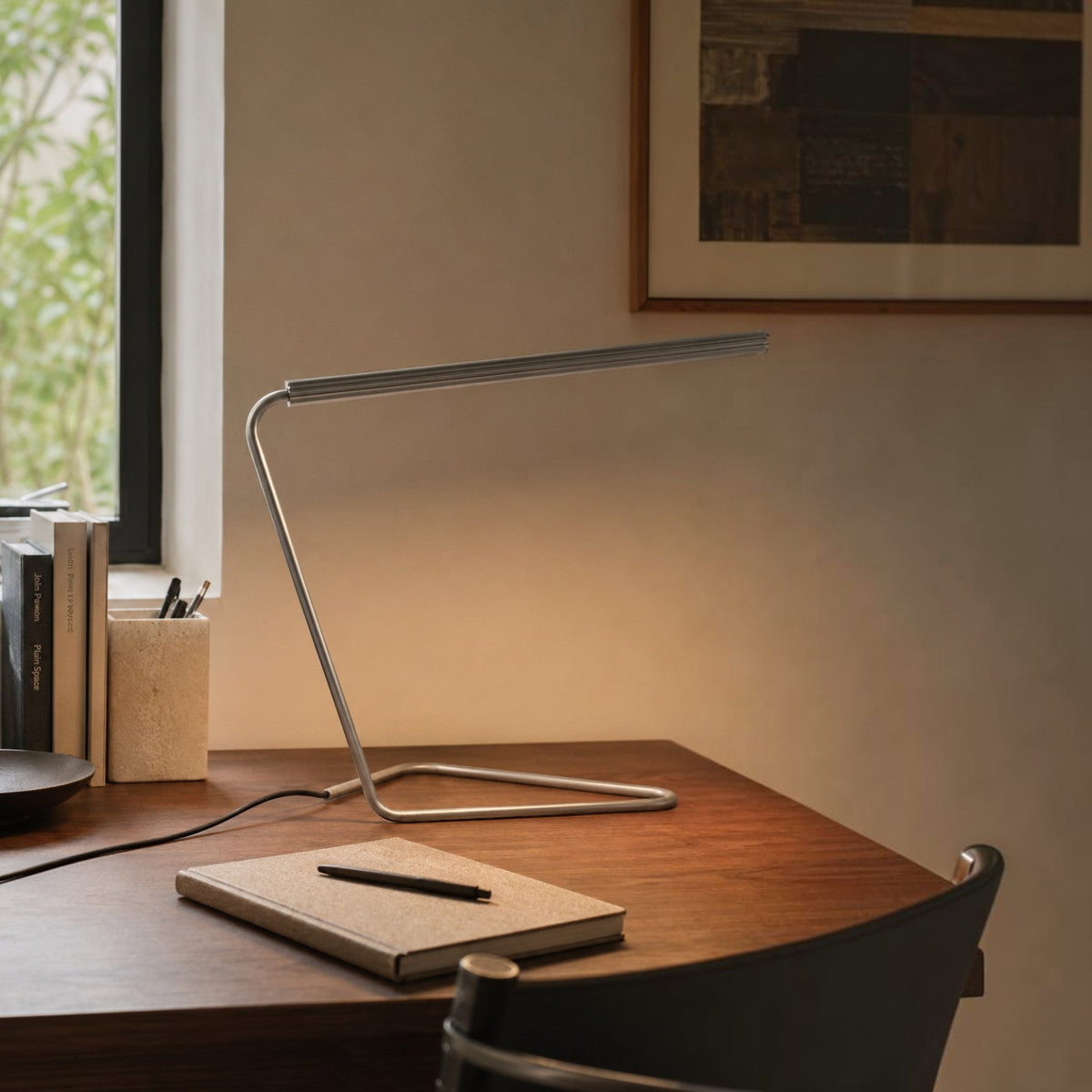 Addo Shop minimalist silver metal LED desk lamp on a wooden office table with a notebook and pen.