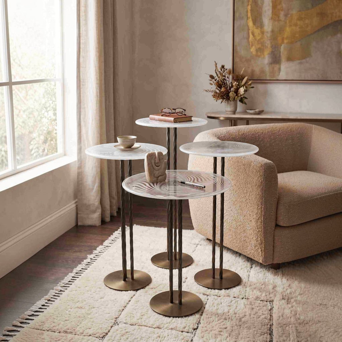 Addo Shop NAVIN Quartet nest of tables with circular glass tops and textured bronze metal stands in a living room.