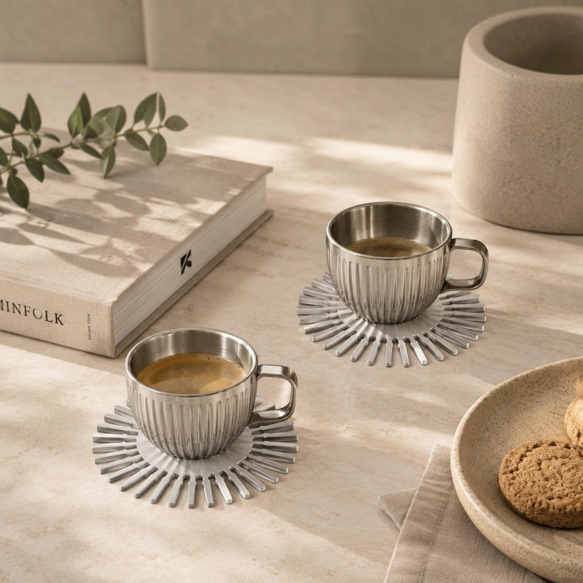 Addo Shop NE-BU-LA stainless steel espresso cups with ribbed texture on sunburst coasters on a beige stone surface