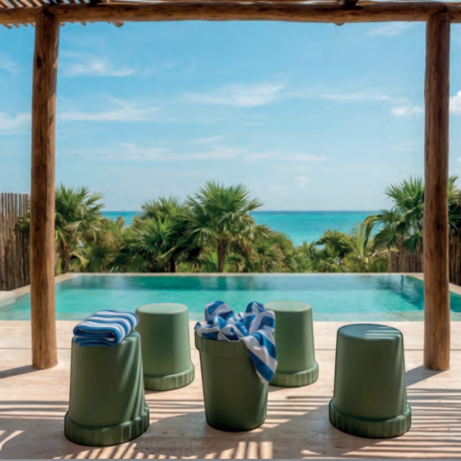 Addo Shop Raffles System Stool set in sage green on a tropical patio overlooking a swimming pool and ocean.