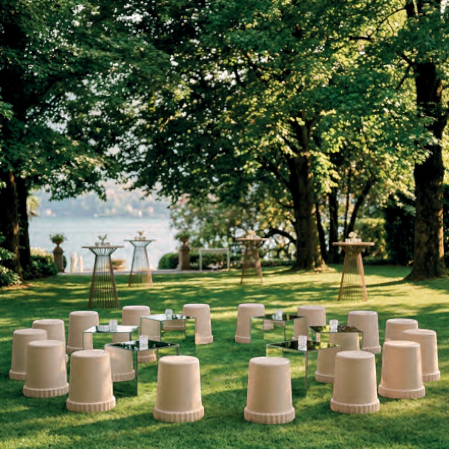 Addo Shop Raffles System Stool set arranged in a circle on a lush green lawn with mirrored side tables.