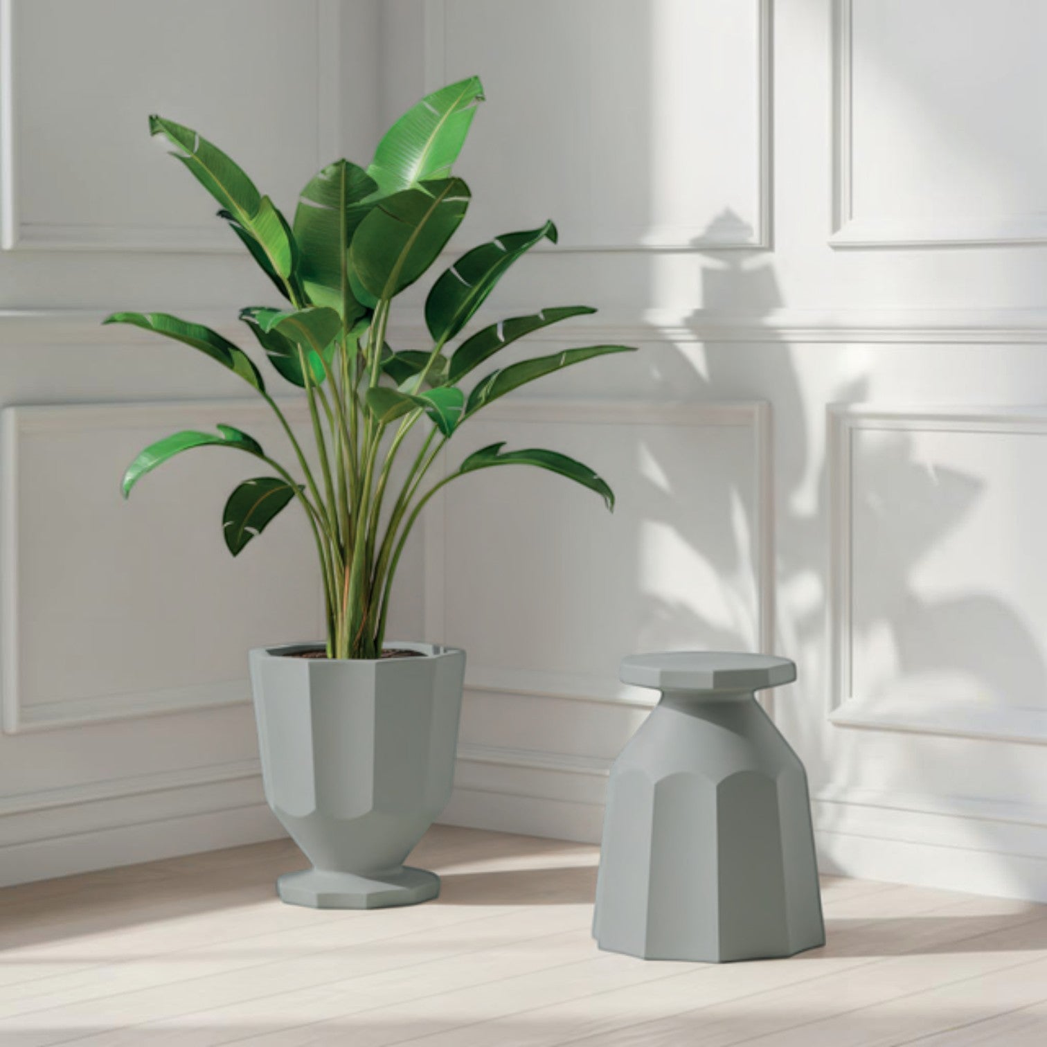 Addo Shop Caimi RECYCLED grey fluted planter holding a large green plant next to a matching stool in a bright room.