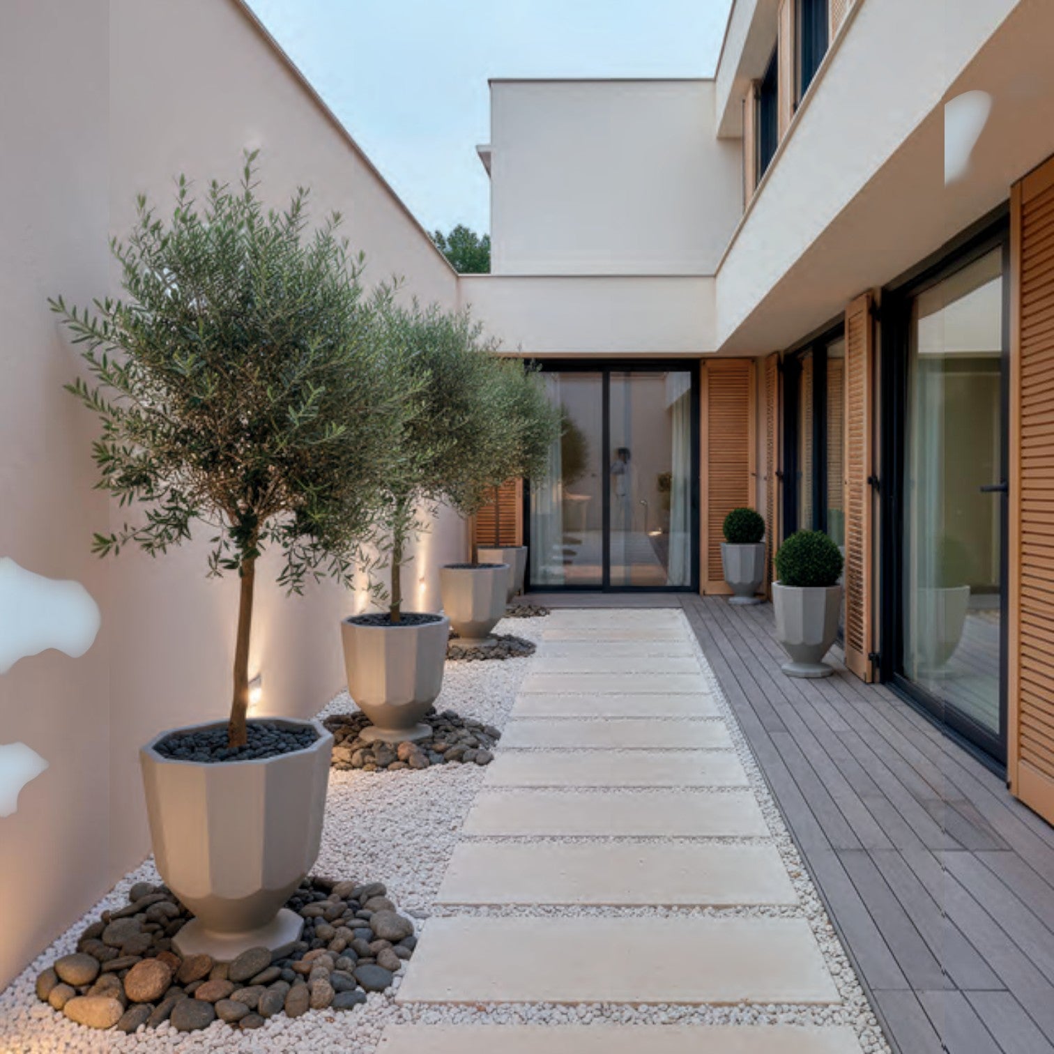 Addo Shop Caimi RECYCLED grey faceted planters lining a modern outdoor patio walkway with olive trees.
