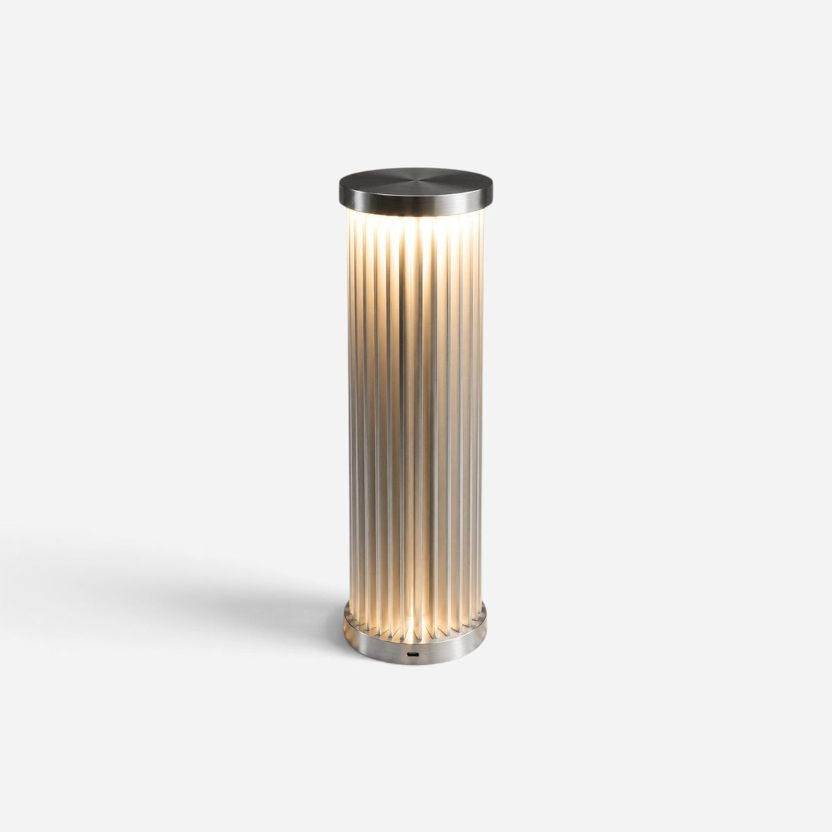 Addo Shop ŞEMS-2 cylindrical table lamp featuring fluted glass and a brushed aluminum frame with warm ambient lighting.