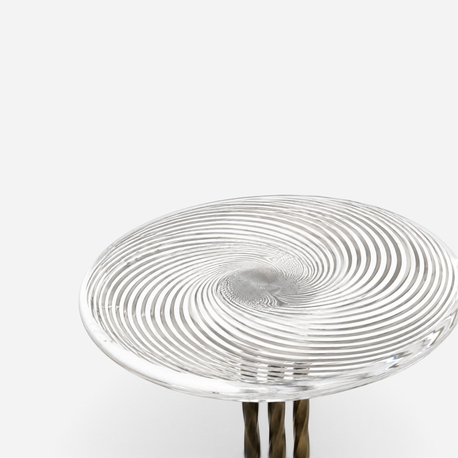 Addo Shop side table with a clear glass top featuring a swirling spiral pattern and a metallic twisted base.