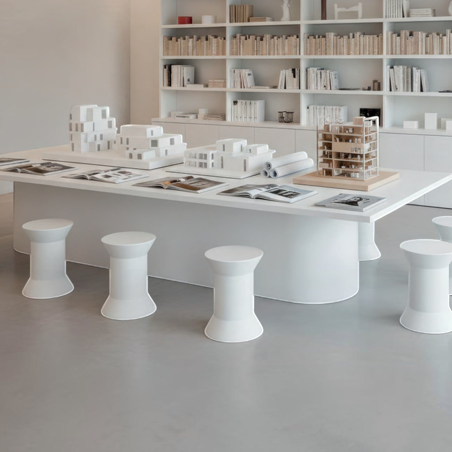 Addo Shop STILEMI Round white minimalist stools arranged around a large table in a modern architectural studio.