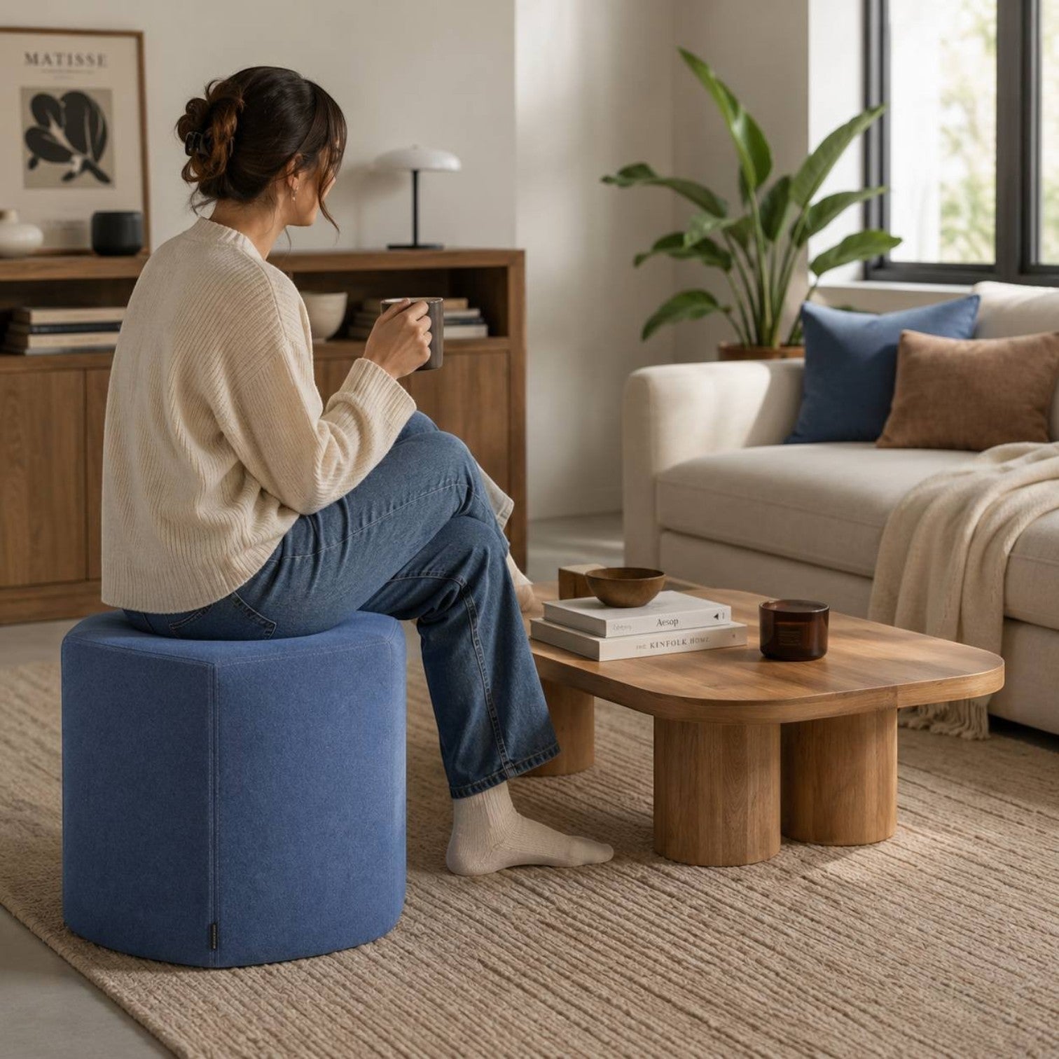 Addo Shop Swap Puf Kare in blue fabric, a compact upholstered round ottoman in a modern living room setting.