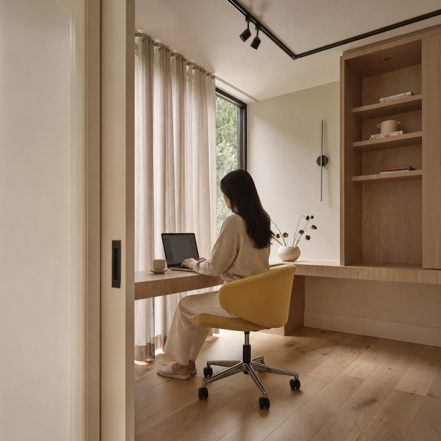 Addo Shop Wing Low Office Chair in yellow with chrome base, used by a woman working at a desk in a modern home office.