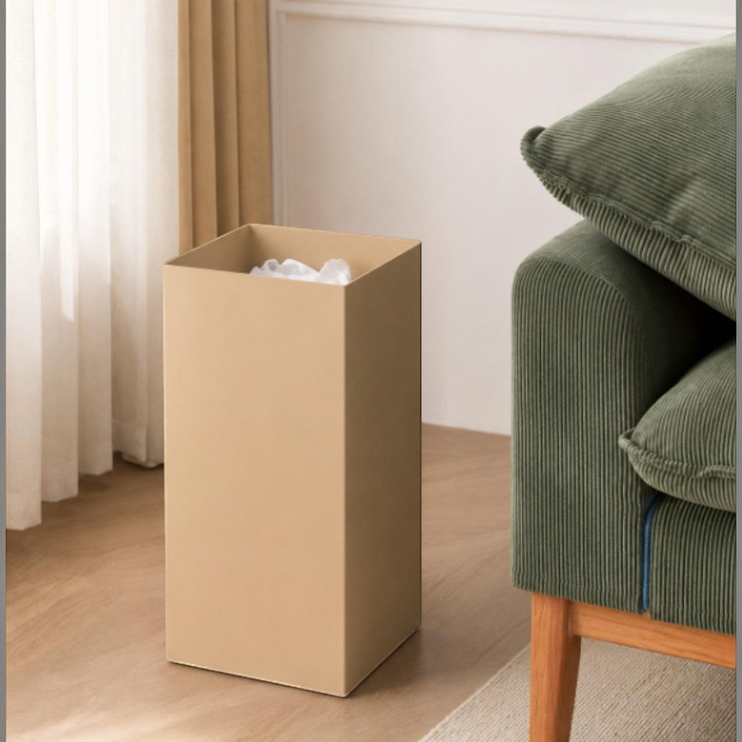 Addo Shop beige 20L rectangular metal waste bin with a minimalist design, shown next to a green corduroy sofa.
