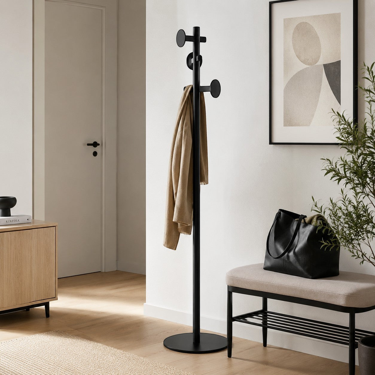 Addo Shop black metal coat stand with circular base and multiple hooks, holding a beige scarf.