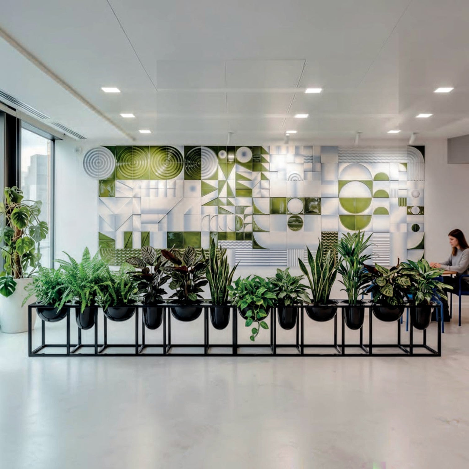 Addo Shop Florianopolis planter with a geometric green and white tiled wall backdrop and various indoor plants.