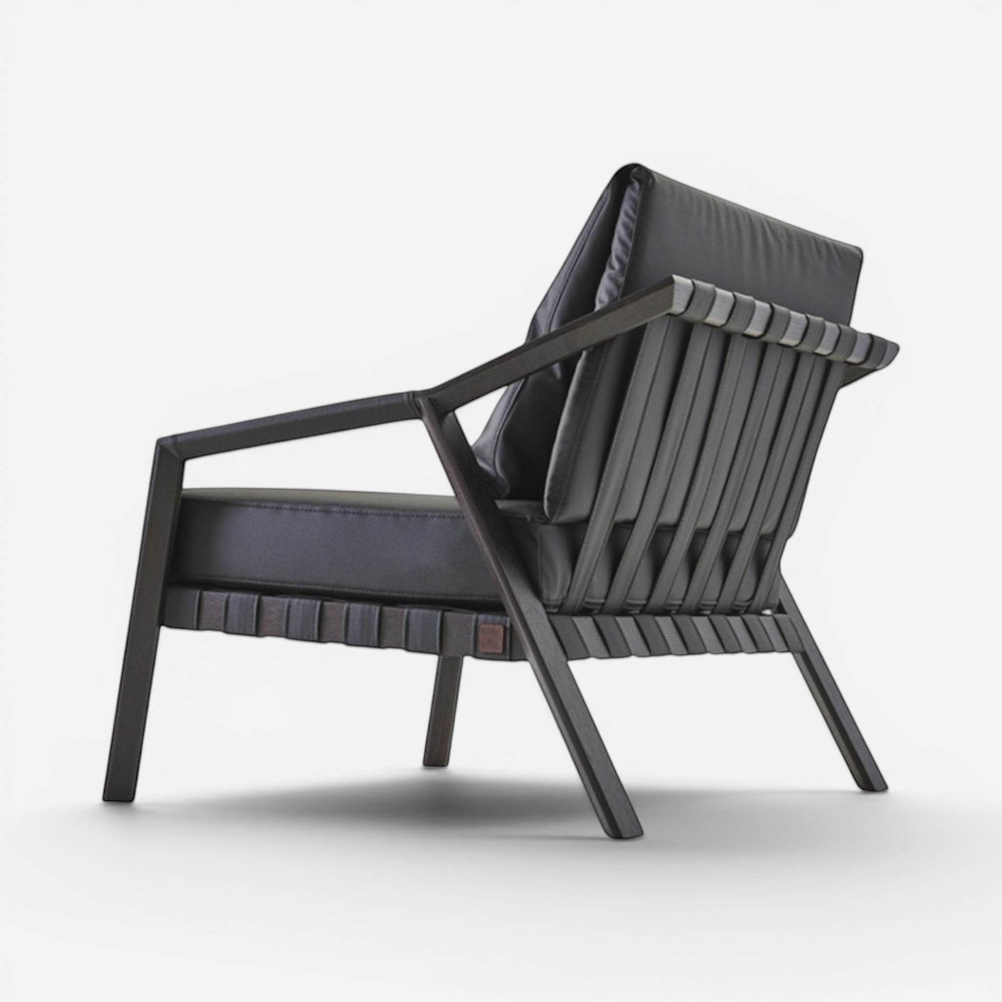 Addo Shop Lares lounge chair with oak solid wood frame and black faux leather upholstery. Modern armchair with woven back detail.