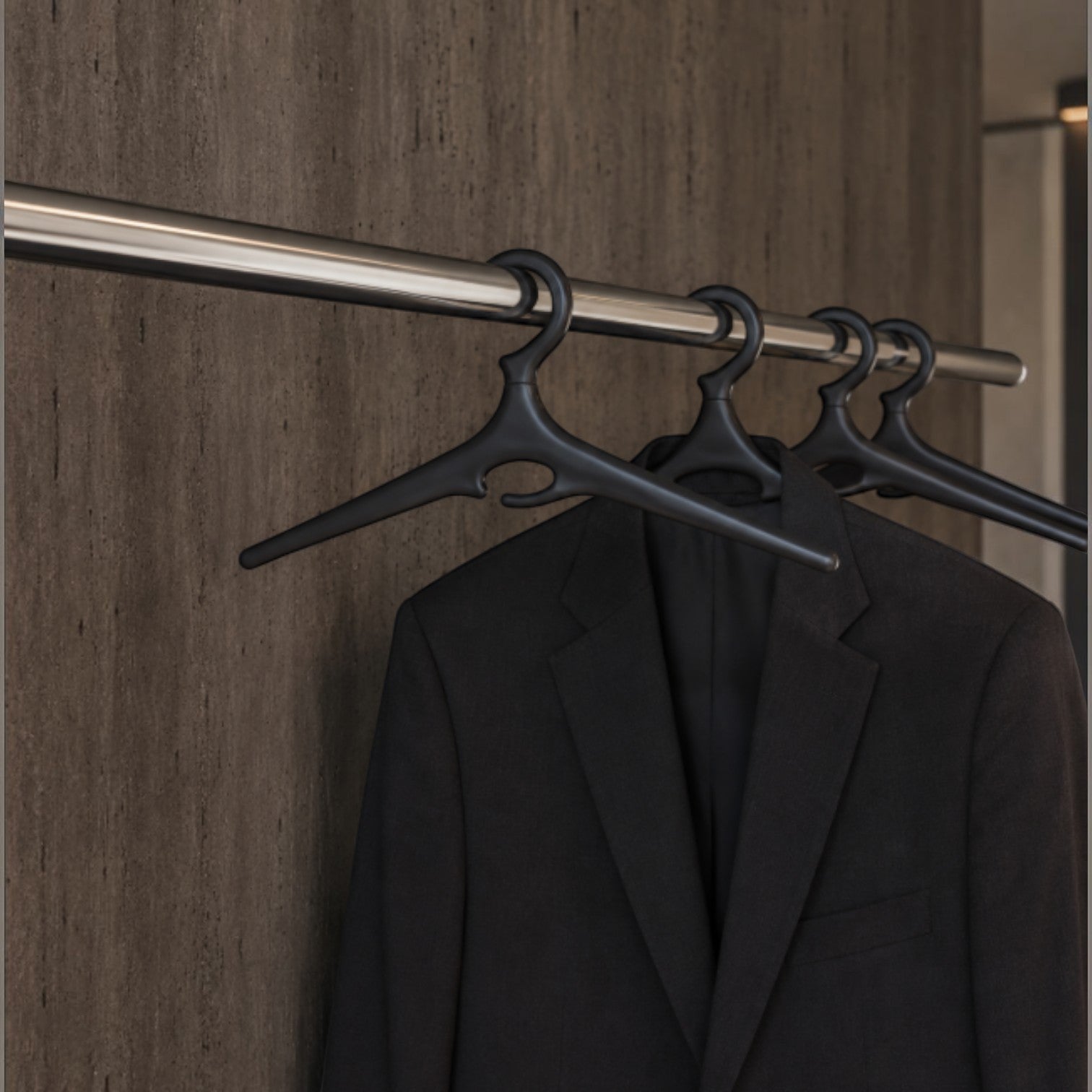 Addo Shop Ometto black plastic coat hangers with a suit jacket hanging on one.