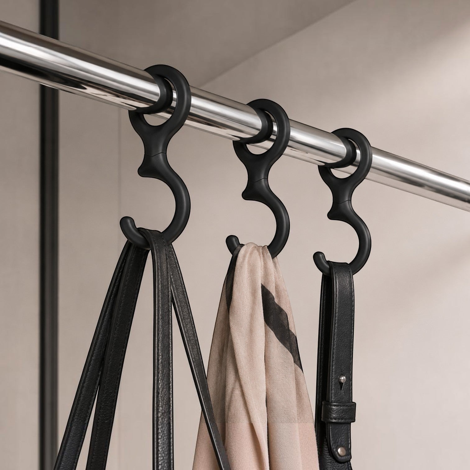 Addo Shop black plastic Ometto hook hanging on a closet rod, holding a black handbag and a beige scarf.