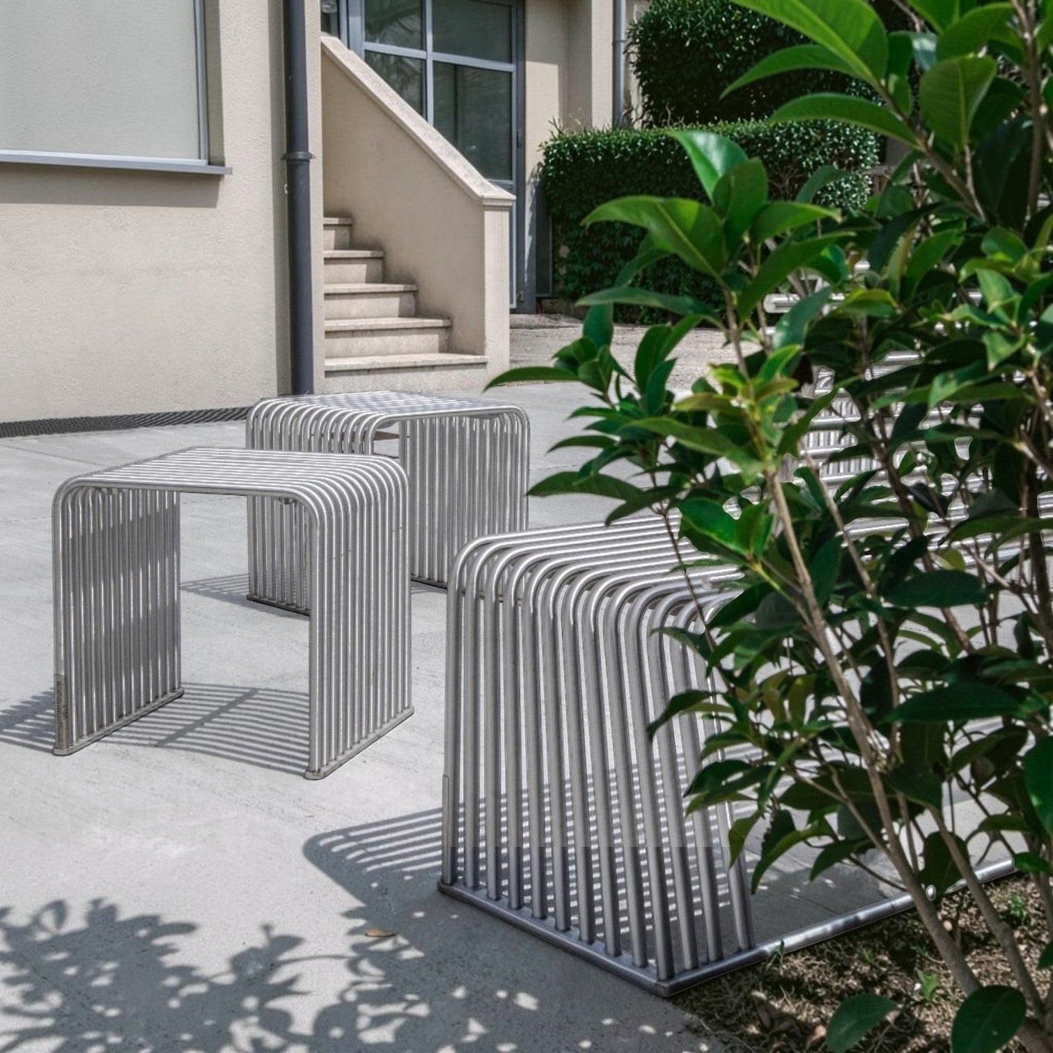 Addo Shop modern silver stainless steel bench with curved legs and slatted seat, designed for outdoor use.